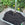 Wheelbarrow filled cow compost and a shovel in a garden setting with a brick wall in the background.