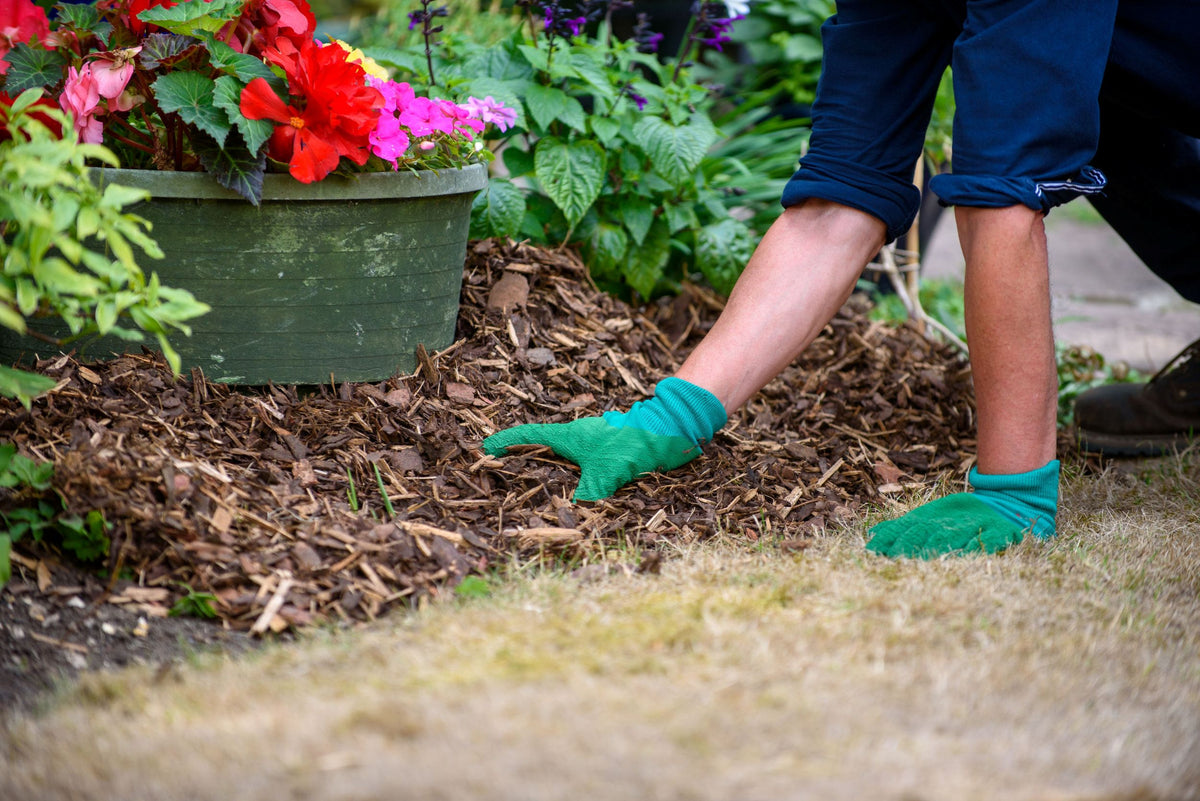 gardening cloves being worn while person lays decorative bark