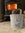 Grey pot with star design in front of a wood stove with fire burning.