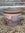 Decorative terracotta pot with butterfly design on a gravel surface.