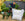 Man unloading woodland mulch from a large bulk bag into a wheelbarrow in a garden setting.