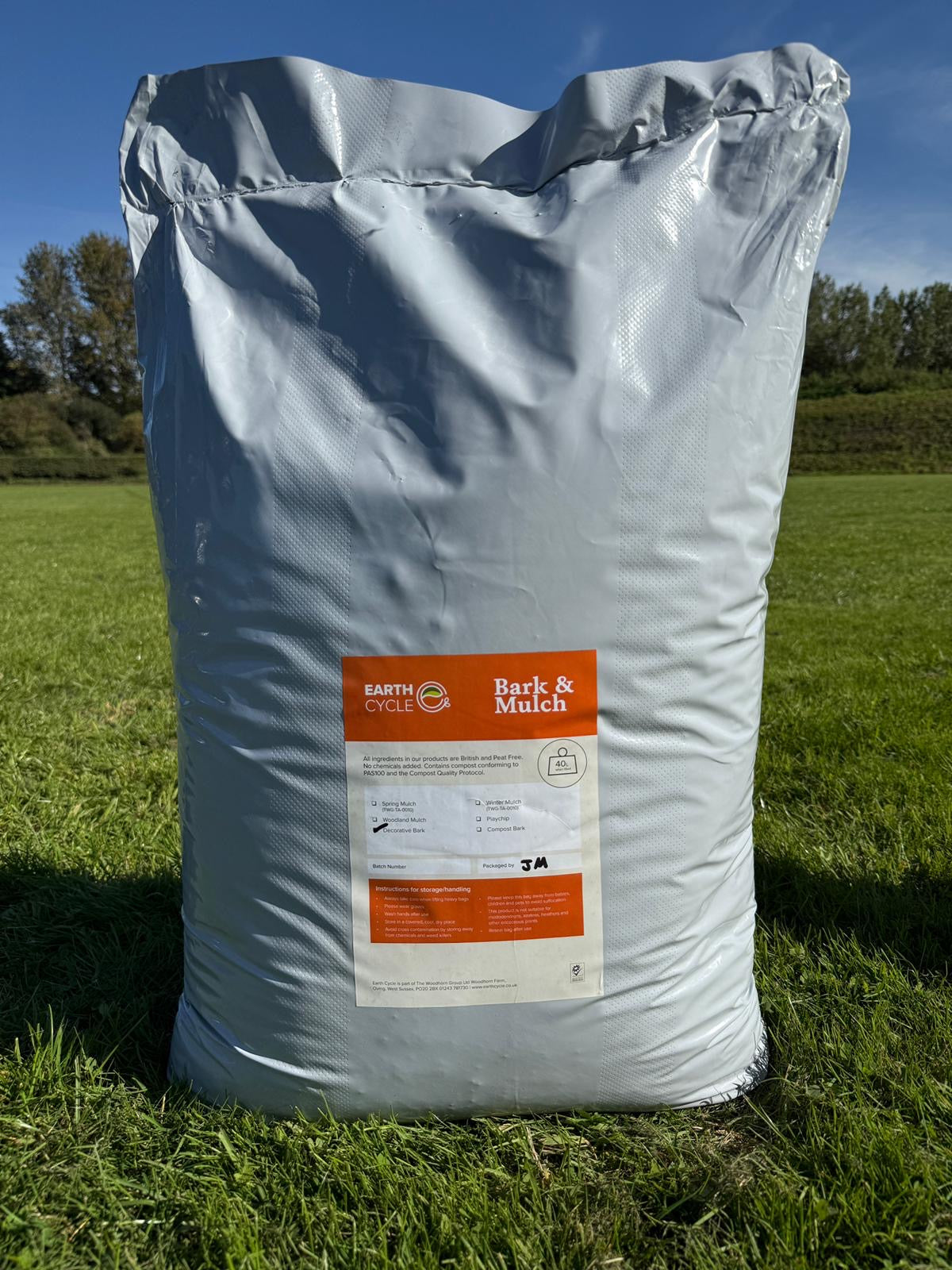 Bag of bark and mulch labeled 'Earth Cycle' on a grassy background