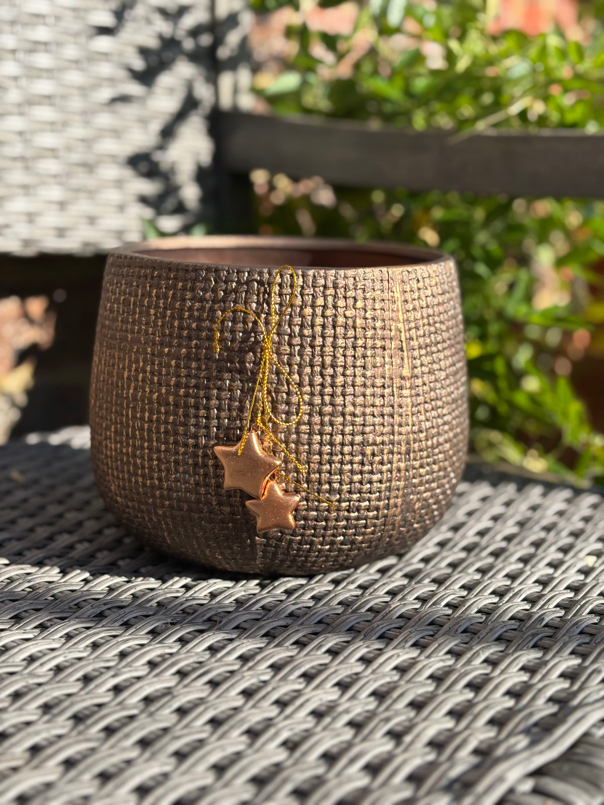 Ceramic pot with star-shaped earrings hanging from it on a textured surface.