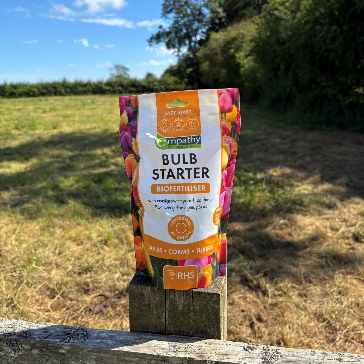 A bag of Bulb Starter fertiliser on a wooden fence outdoors 