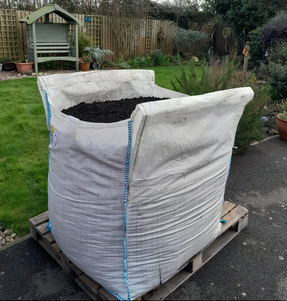 Large topsoil bulk bag on a pallet in a garden setting