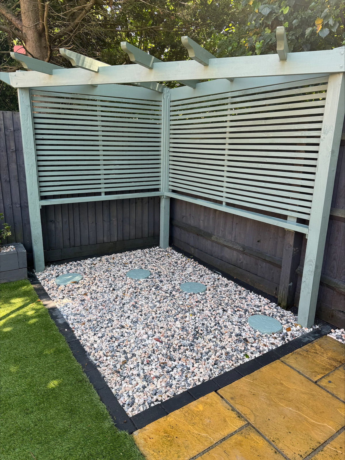 Outdoor shower area with a wooden enclosure and decorative flamingo chippings to floor.