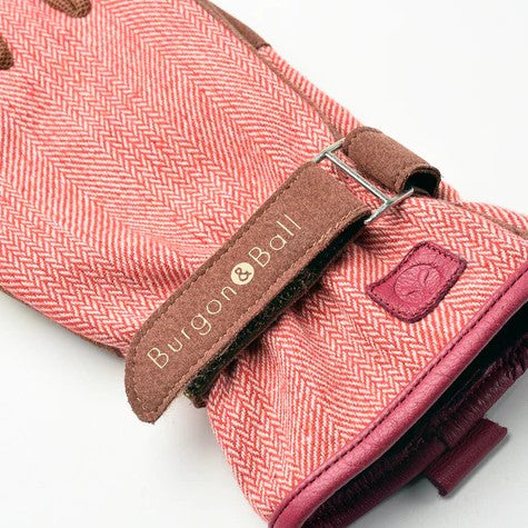Close-up of a red herringbone tie with brown leather strap and Burgon & Ball branding.