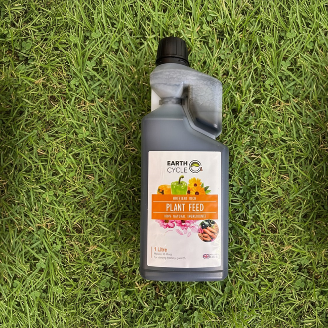 Bottle of plant food on grass background