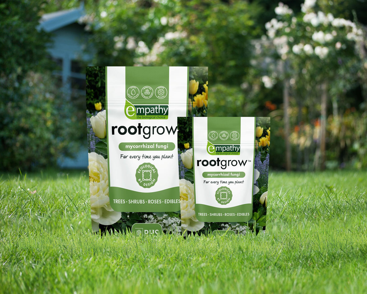 Two packages of empathy rootgrow mycorrhizal fungi on grass with a garden background
